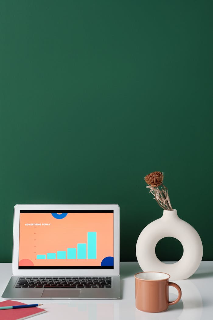 A Silver Laptop Beside a Mug on White Desk